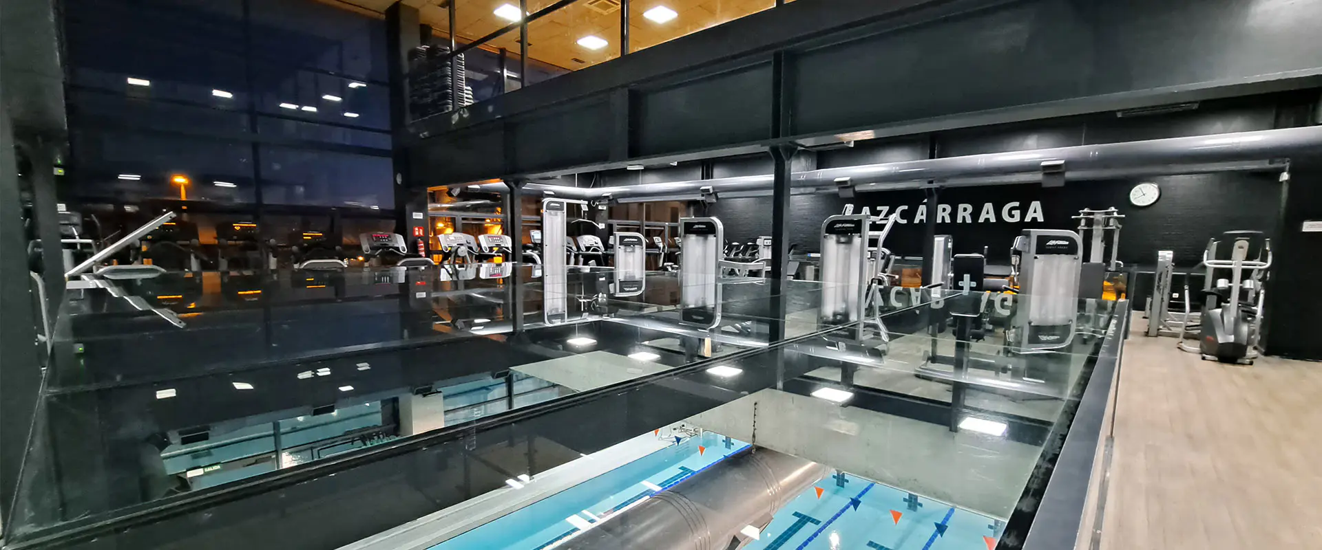 Vista general de la sala de fitness, con diversas máquinas de ejercicio. Vista parcial de la piscina del piso inferior