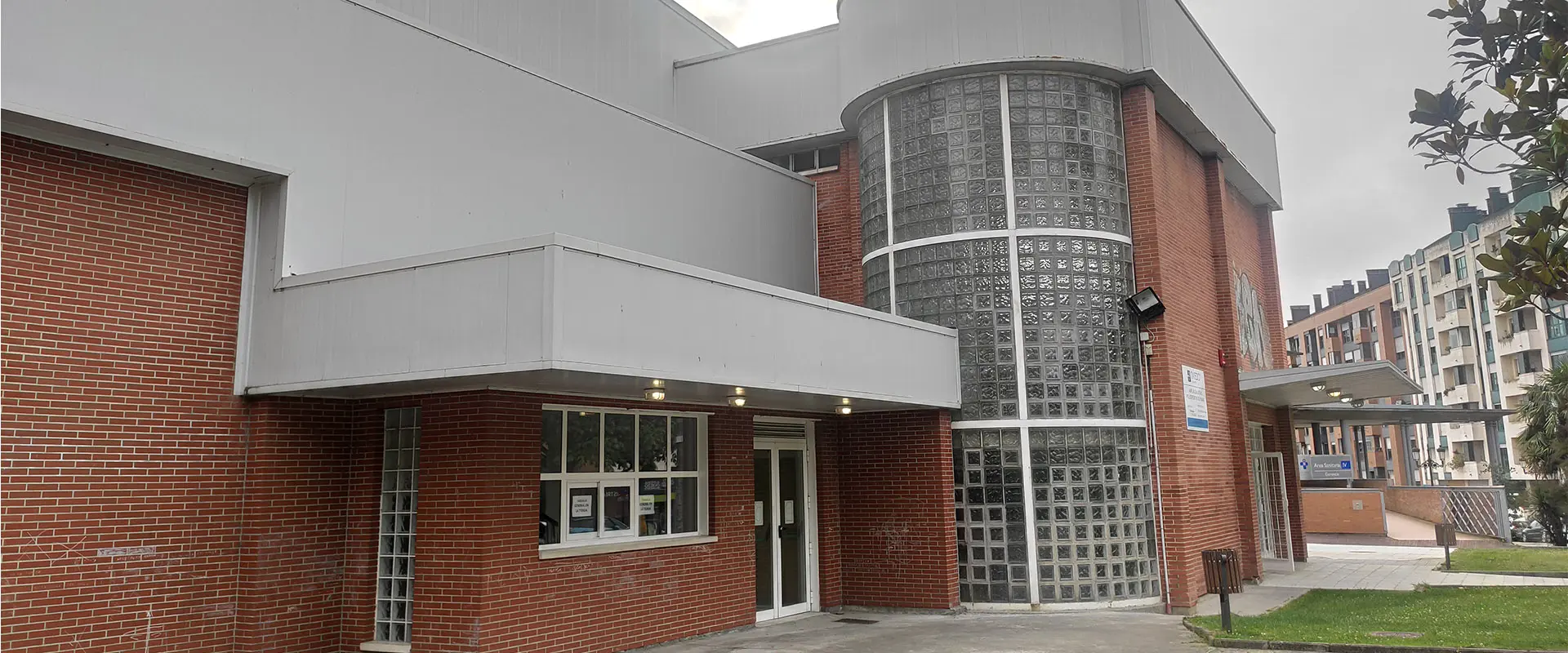 Exterior del polideportivo. Puerta principal vidrio, ventana semicircular de vidrio ondulado y transparente en tres alturas