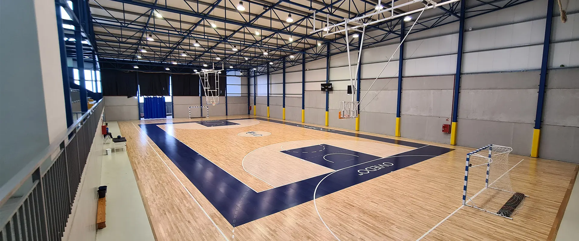 Panorámica de la pista polideportiva desde una esquina de las gradas, con canastas de baloncesto y porterías de fútbol