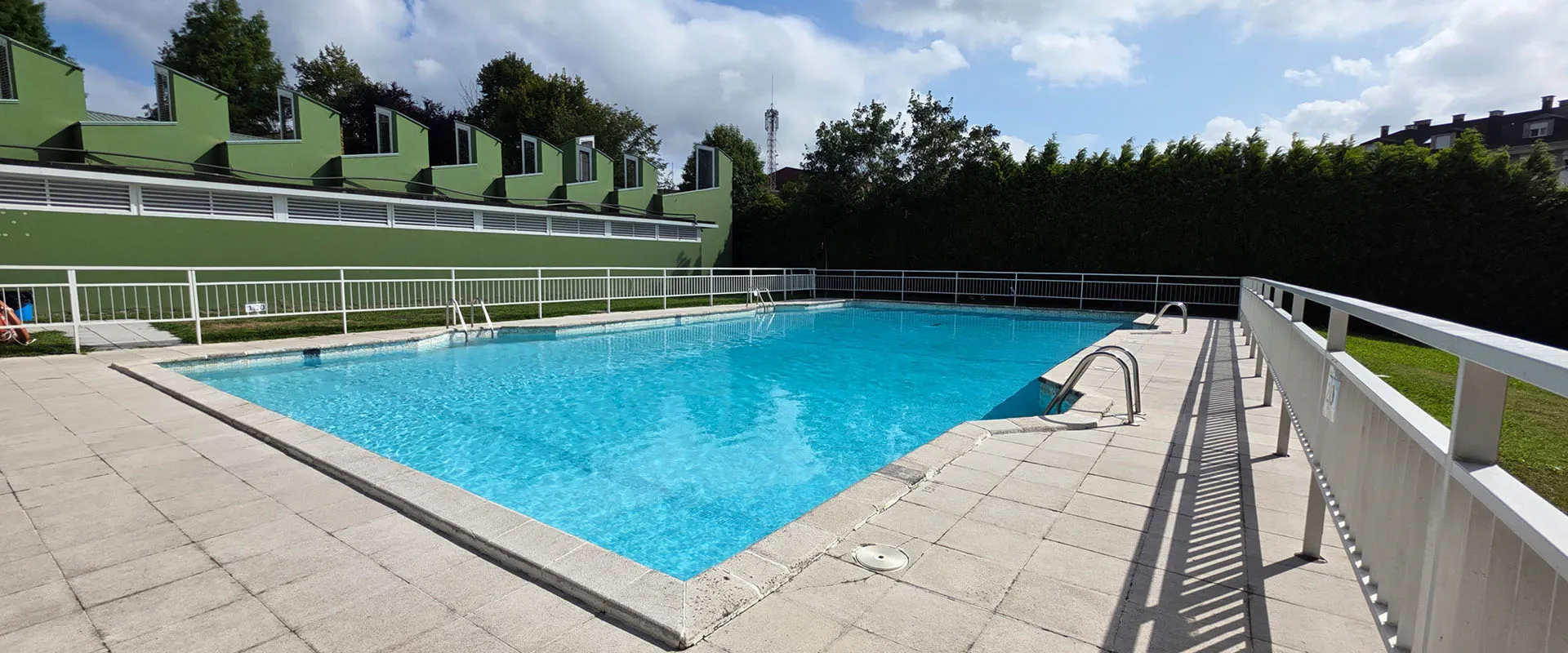 Vista de la piscina desde una esquina. A la izquierda el edificio de servicios