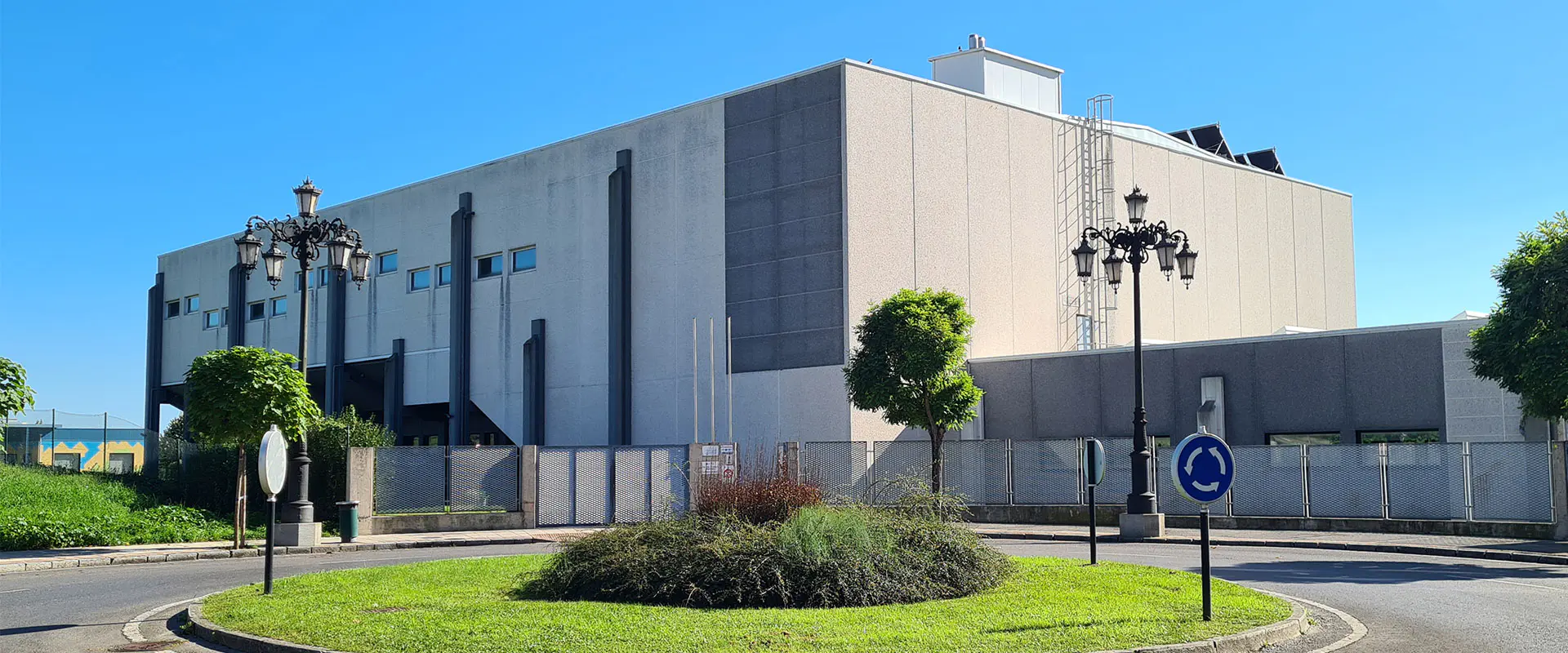 Vista exterior del Centro Deportivo Jorge Egocheaga, con vallas perimetrales y rotonda exterior ajardinada
