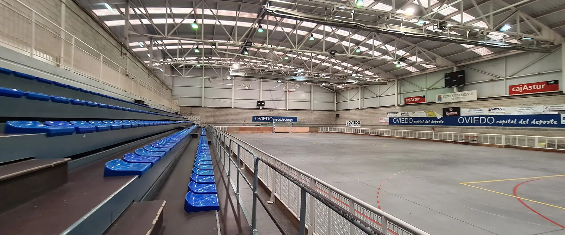 Pista polideportiva de hormigón pulido desde la grada, que se encuentra a la izquierda. Hay una portería al fondo de la pista