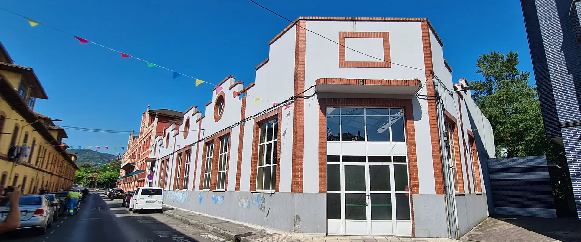 Polideportivo de Trubia. Fachada principal el edificio. Puerta principal metálica blanca con rectángulos de cristal