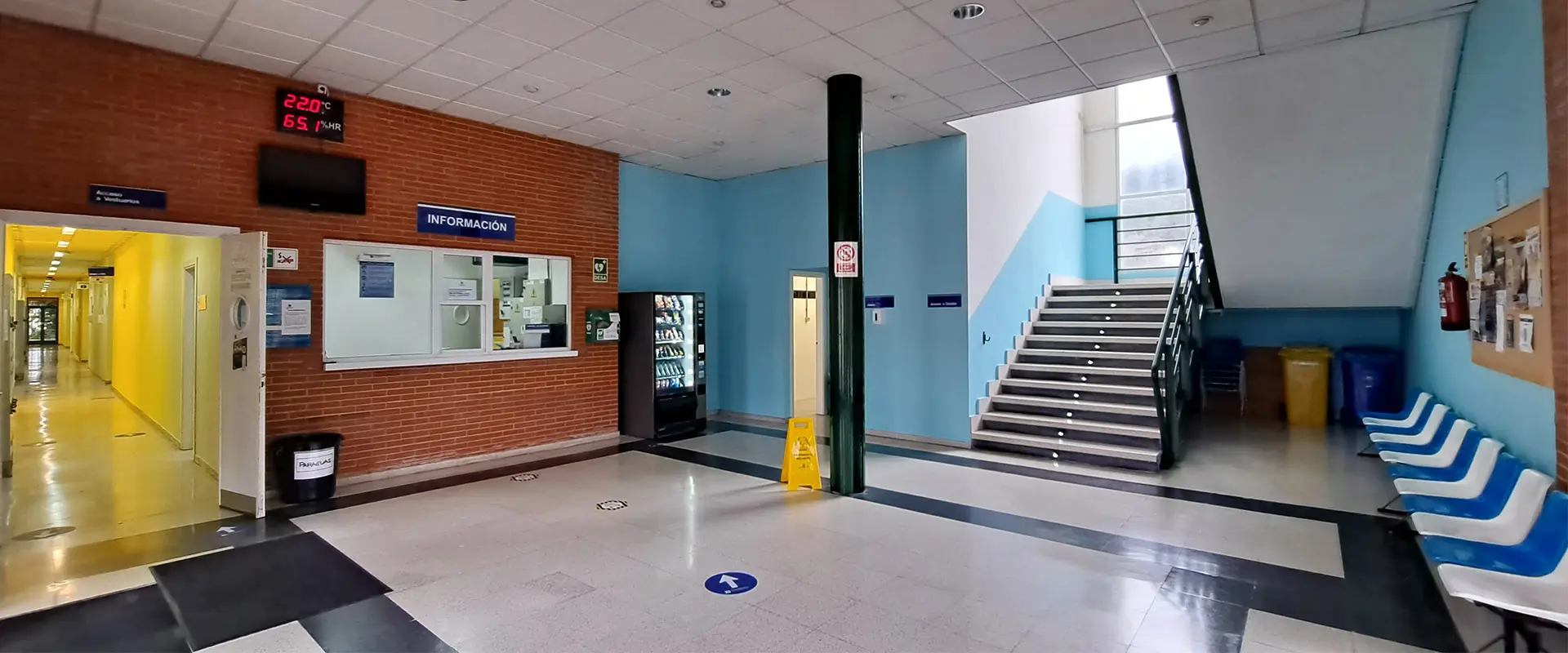 Hall de entrada instalación. Mostrador acristalado de información. Escaleras. Pasillos alargado, acceso a dependencias 