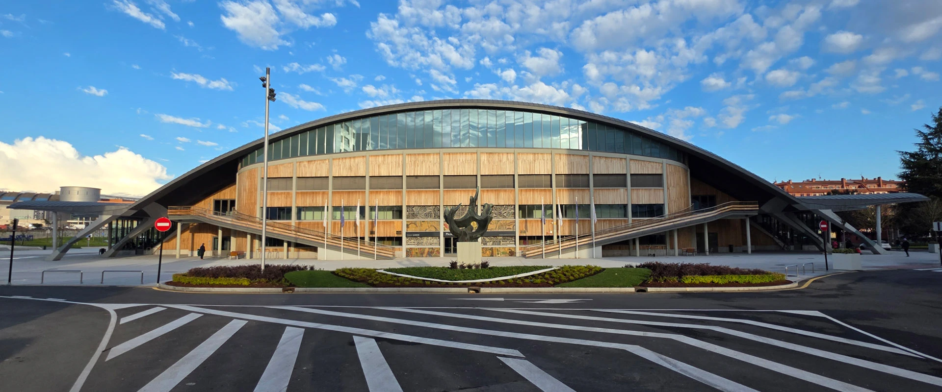 Exterior renovado del palacio con cubierta en forma de caparazón de tortuga, gris de zinc mate y fachada acristalada