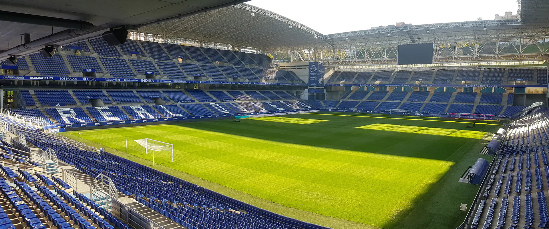 Terreno de juego desde una esquina de las gradas. Vista de las cuatro gradas. Marcador.