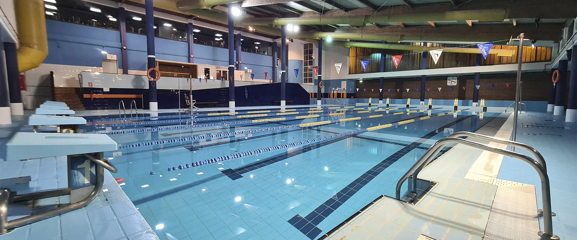 Panorámica de la piscina, con vista en detalle de las plataformas de salida y las barandillas de acceso