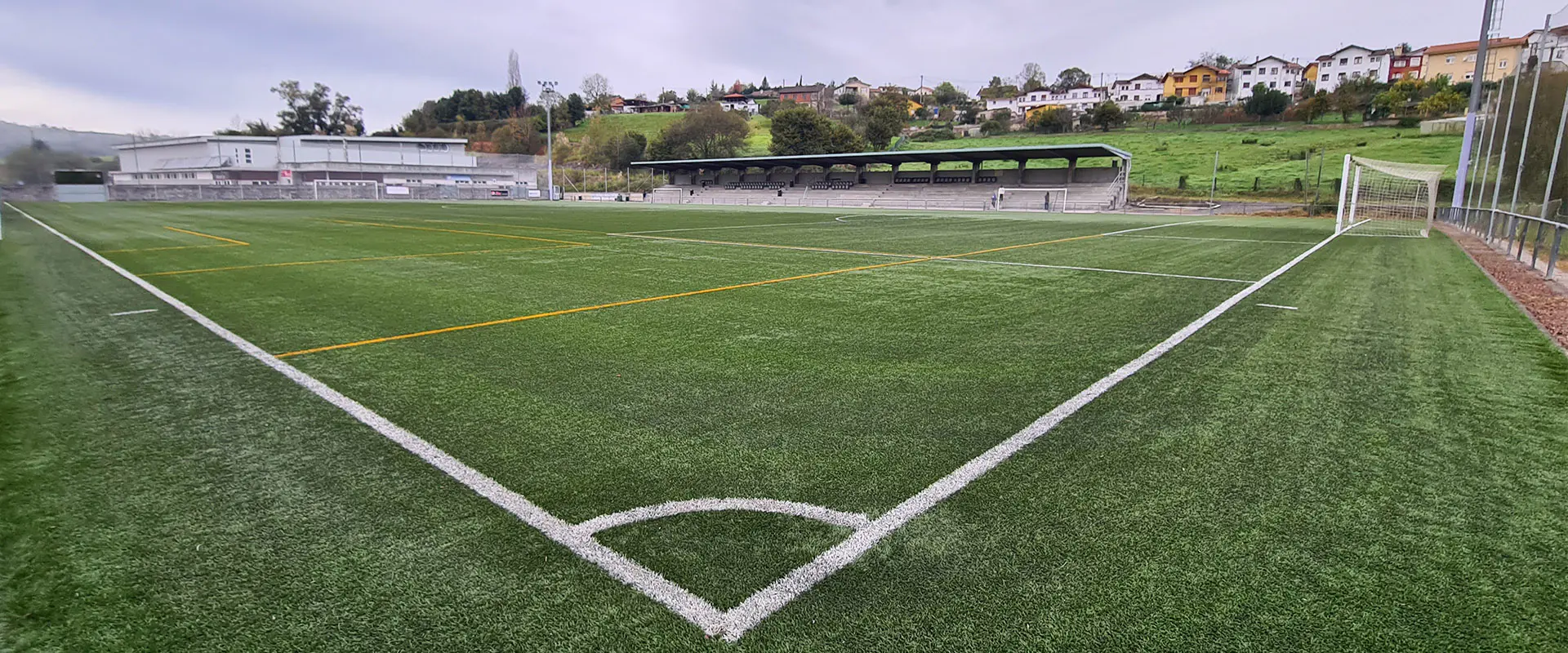 Vista a pie de campo y desde un córner del terreno de juego, con vista de las porterías y las gradas al fondo