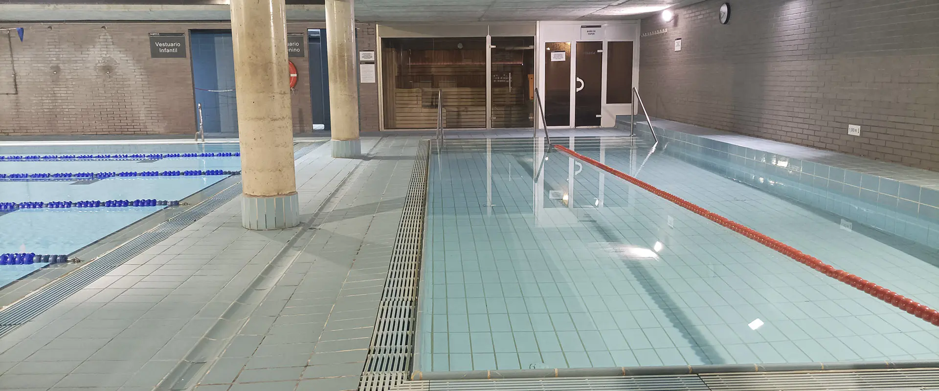 Piscina de aprendizaje climatizada, con una cuerda de seguridad y salas de sauna y vapor al fondo