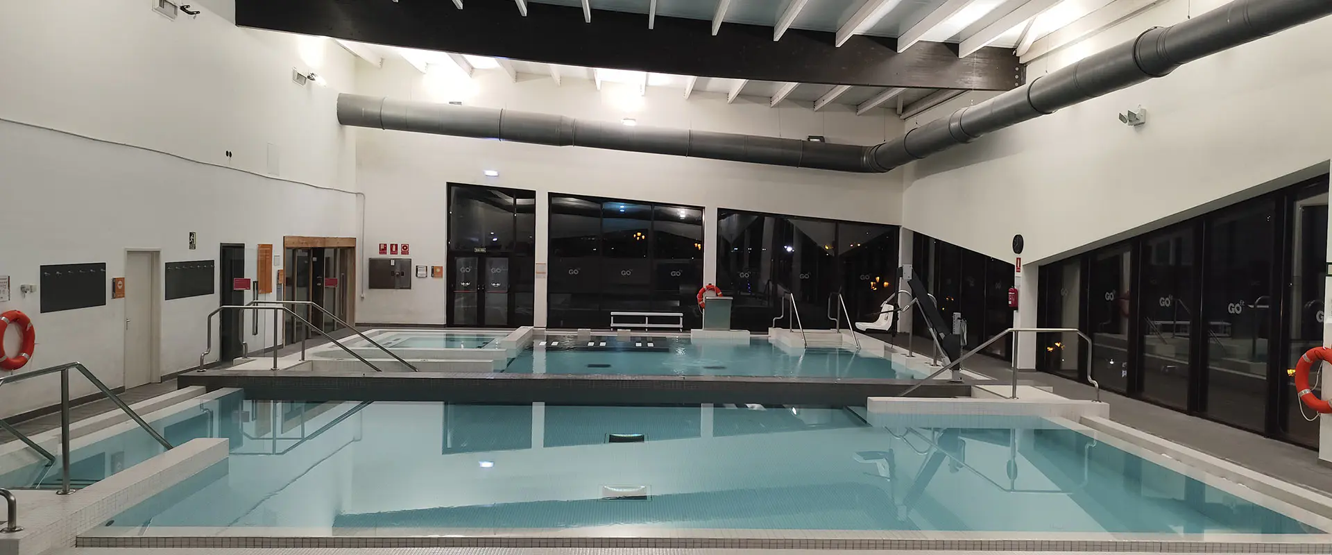 Piscinas de aprendizaje y spa, con la sauna a la izquierda y amplios ventanales al fondo con vistas al exterior