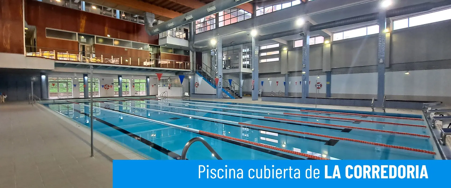 Piscinas cubiertas de La Corredoria. Imagen lateral de la piscina principal. Barandillas de acceso. Piso superior al fondo 
