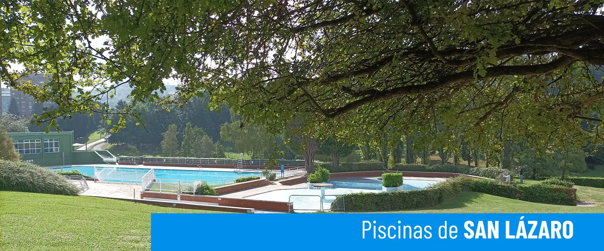 Piscinas de San Lázaro. Foto general de la piscina principal. A su lado la piscina infantil, rodeada de jardines y vegetación 