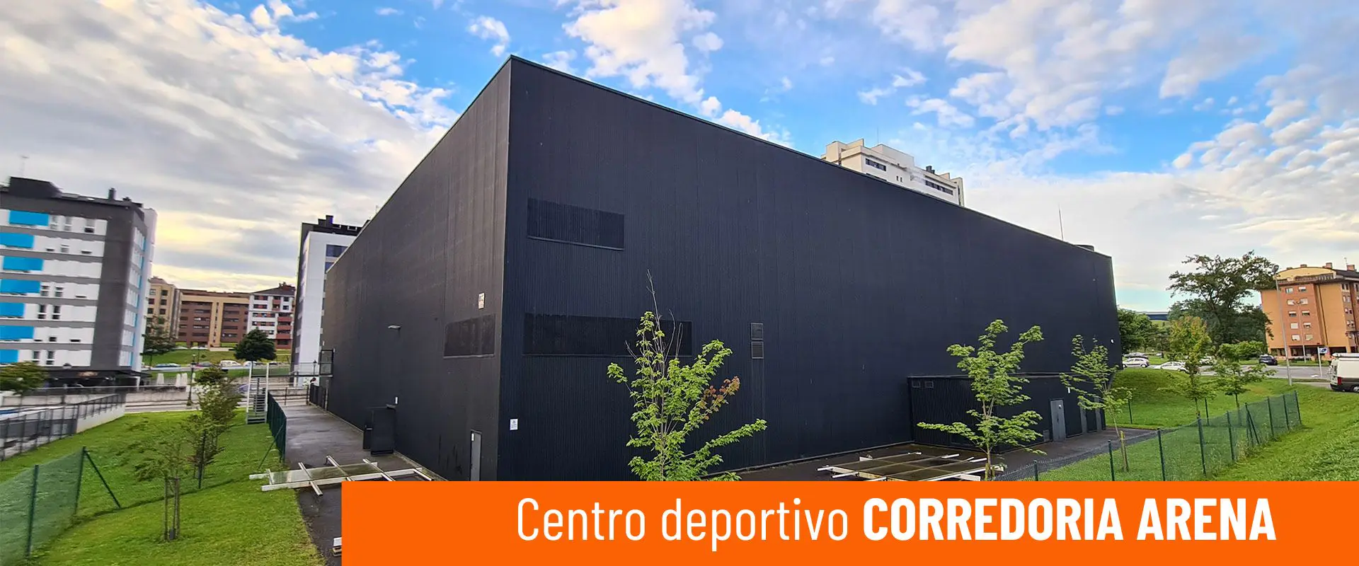 Centro Deportivo Corredoria Arena. Imagen exterior del edificio y áreas ajardinadas circundantes 