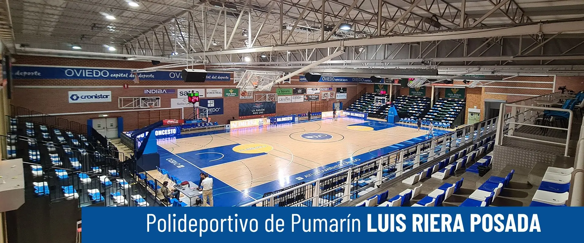 Polideportivo de Pumarín Luis Riera Posada. Pista polideportiva desde las gradas. Mesa de anotaciones con personas alrededor 