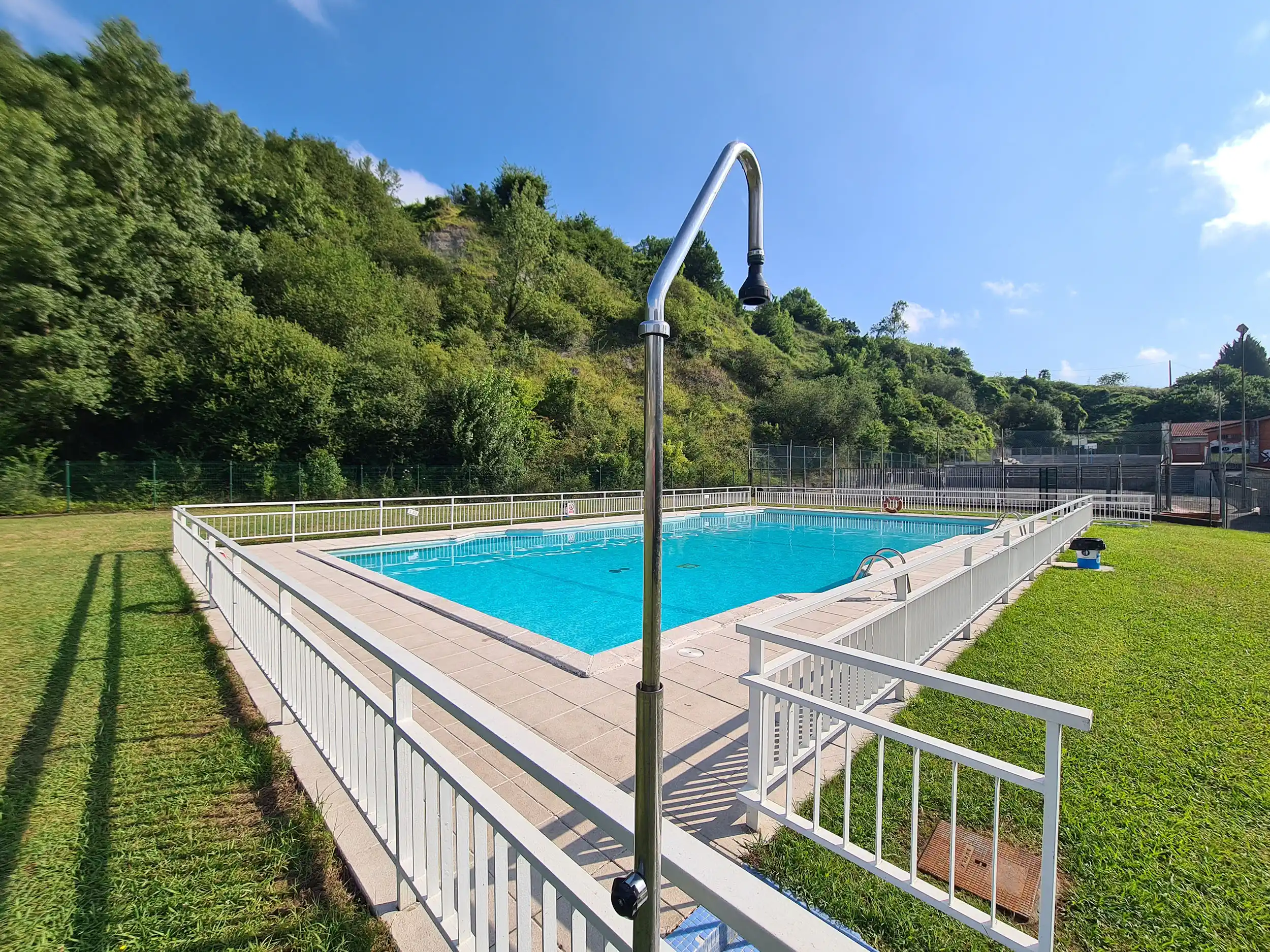 zona de acceso a la piscina con la ducha en primer plano