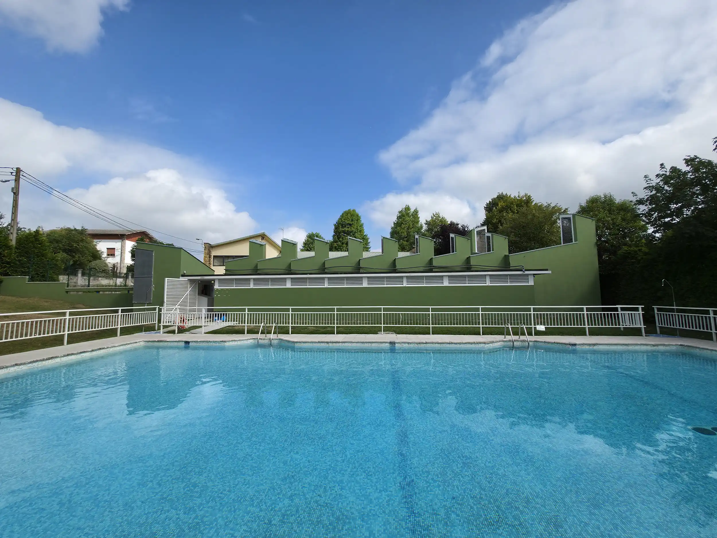 vista de la piscina desde un lateral y el edificio de servicios al fondo