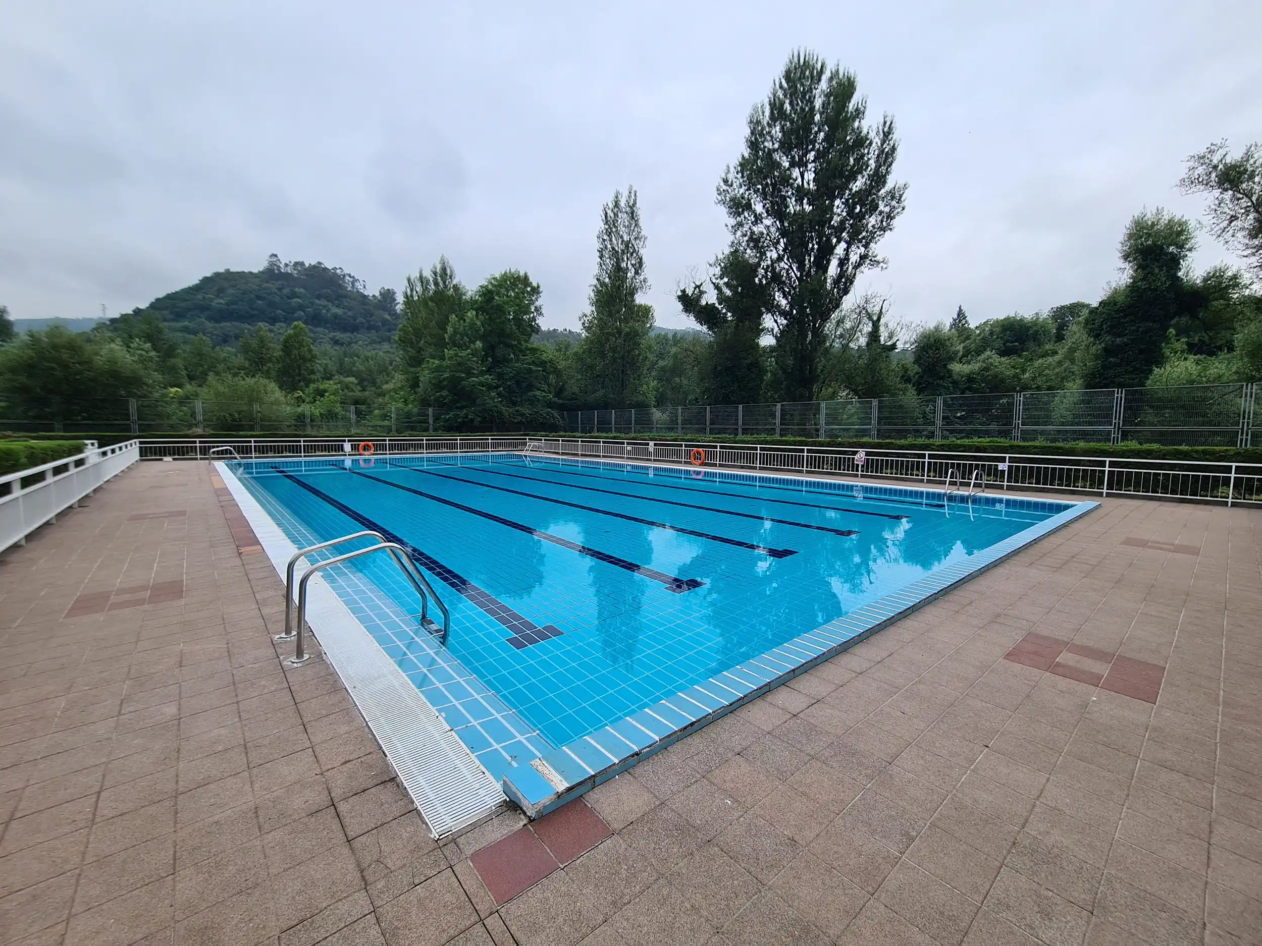 vista de la piscina desde una esquina con escaleras de acceso en primer plano