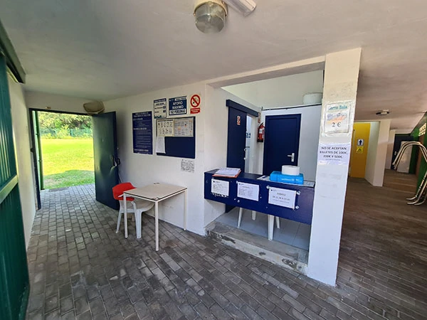 Acceso a la instalación con pasillos de acceso a la piscina, a los vestuarios y mostrador de atención al público