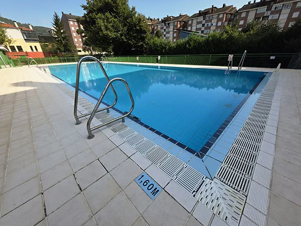 vista de la piscina desde una esquina con escaleras de acceso en primer plano